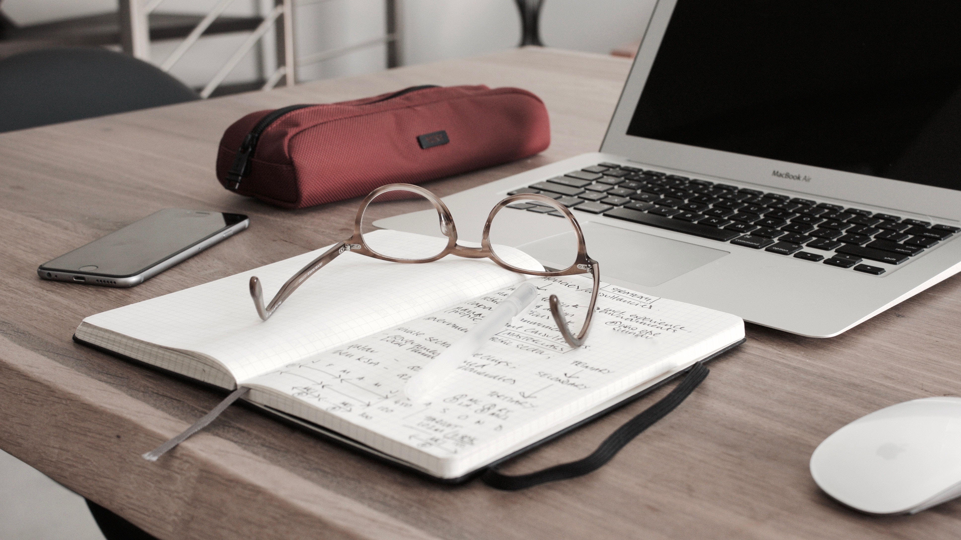 Laptop, notebook, and glasses on table